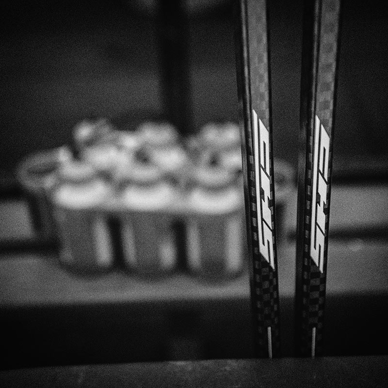Two 12K carbon fiber hockey sticks sitting behind the bench.
