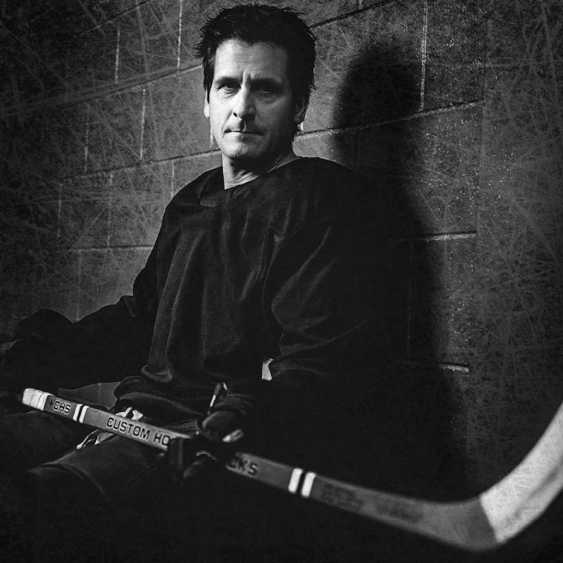 Man holding vintage Custom Hockey Stick in locker room.