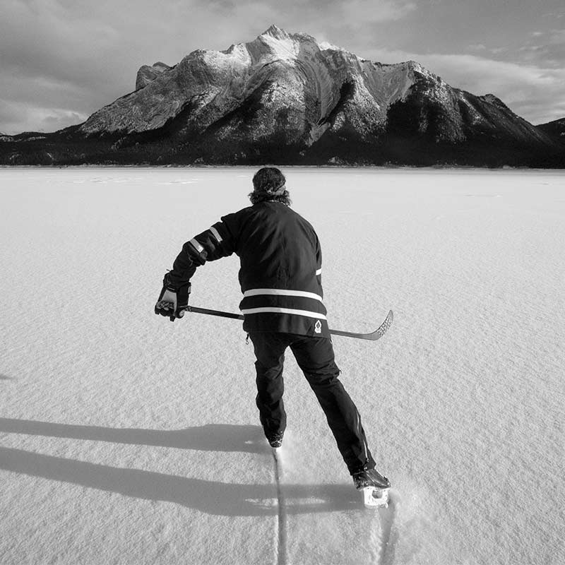 Hockey player skating on a frozen lake covered with snow in the rockies.